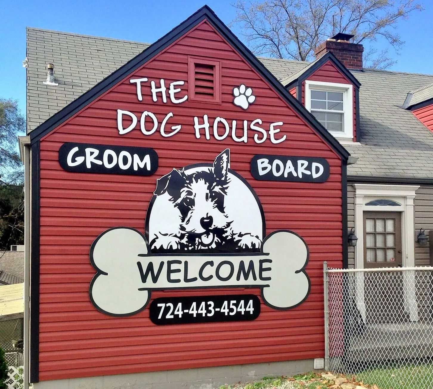Red Dog House building with a dog graphic, advertising grooming and boarding. Phone number and