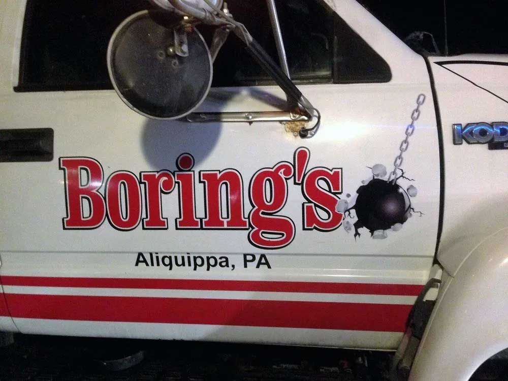 Boring's truck door with logo: red lettering, a wrecking ball breaking through, white door, and the city Aliquippa, PA.