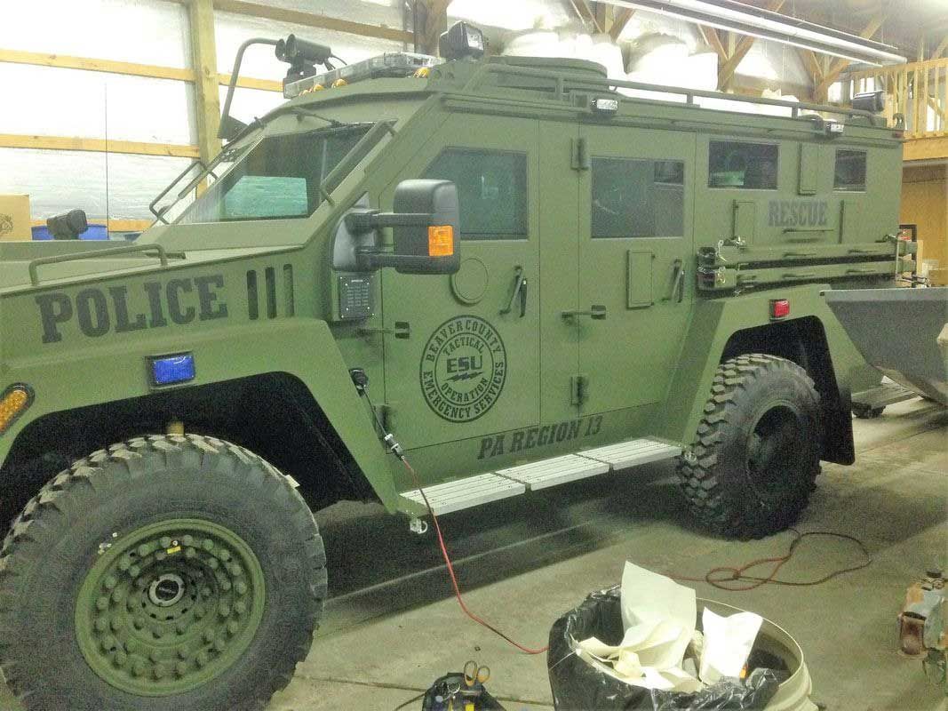 Green armored police vehicle parked in a garage. 