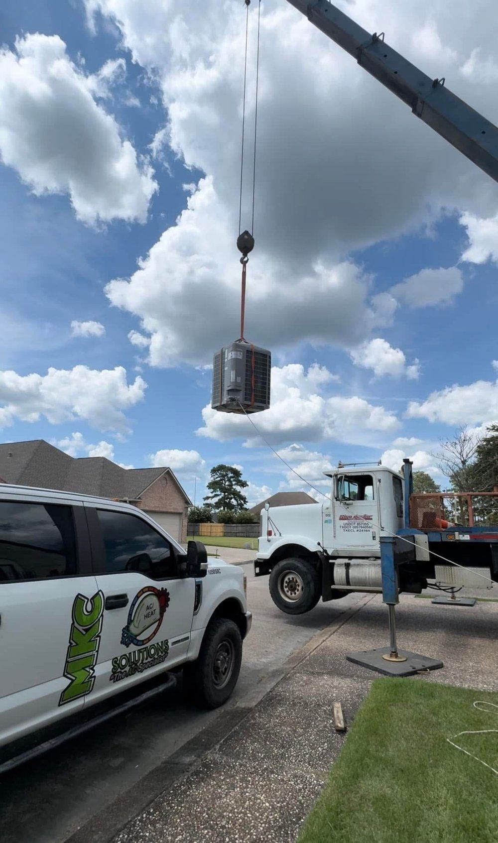 A truck is being lifted by a crane in a driveway.