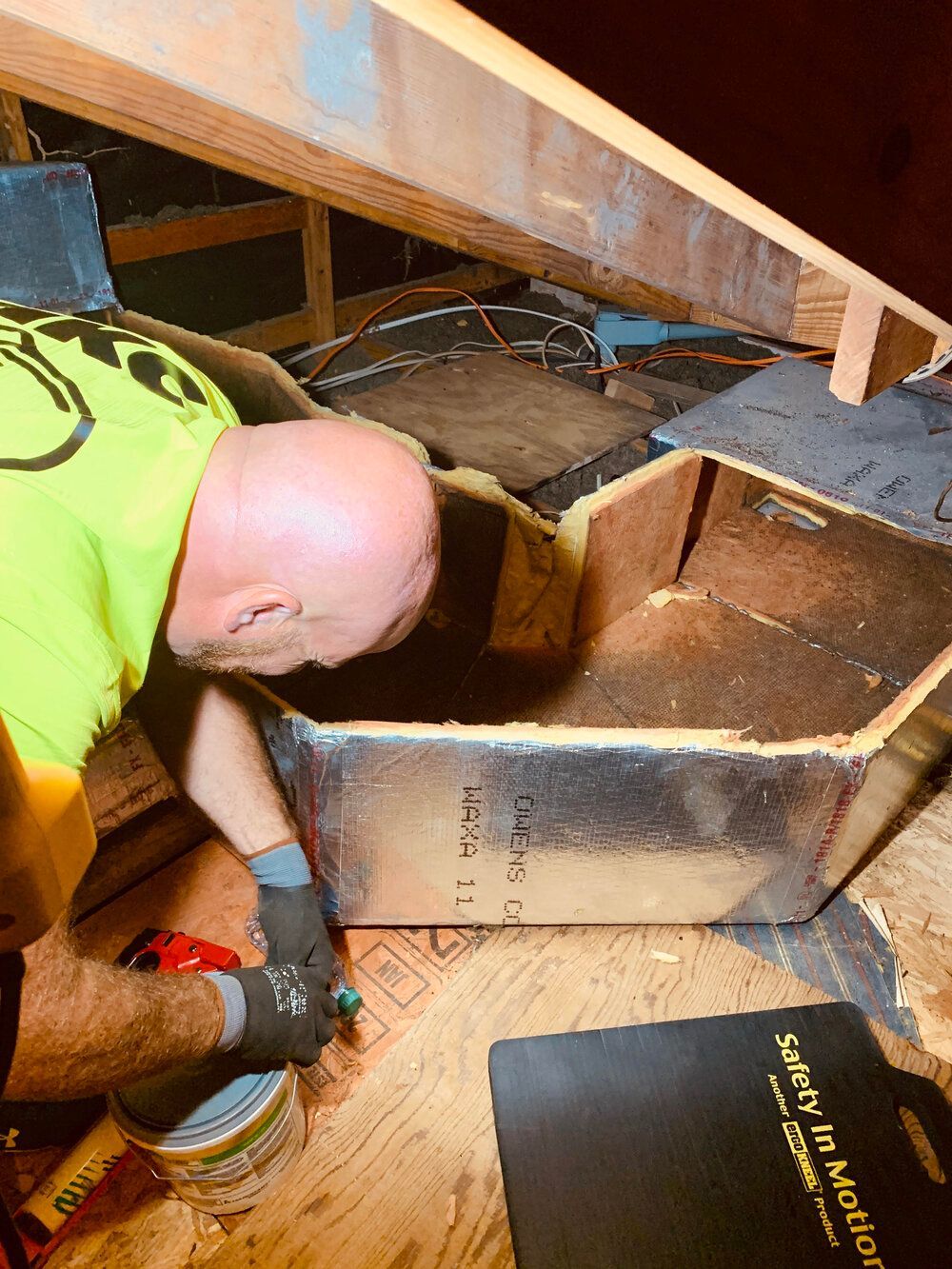 A man is working on a box in an attic.