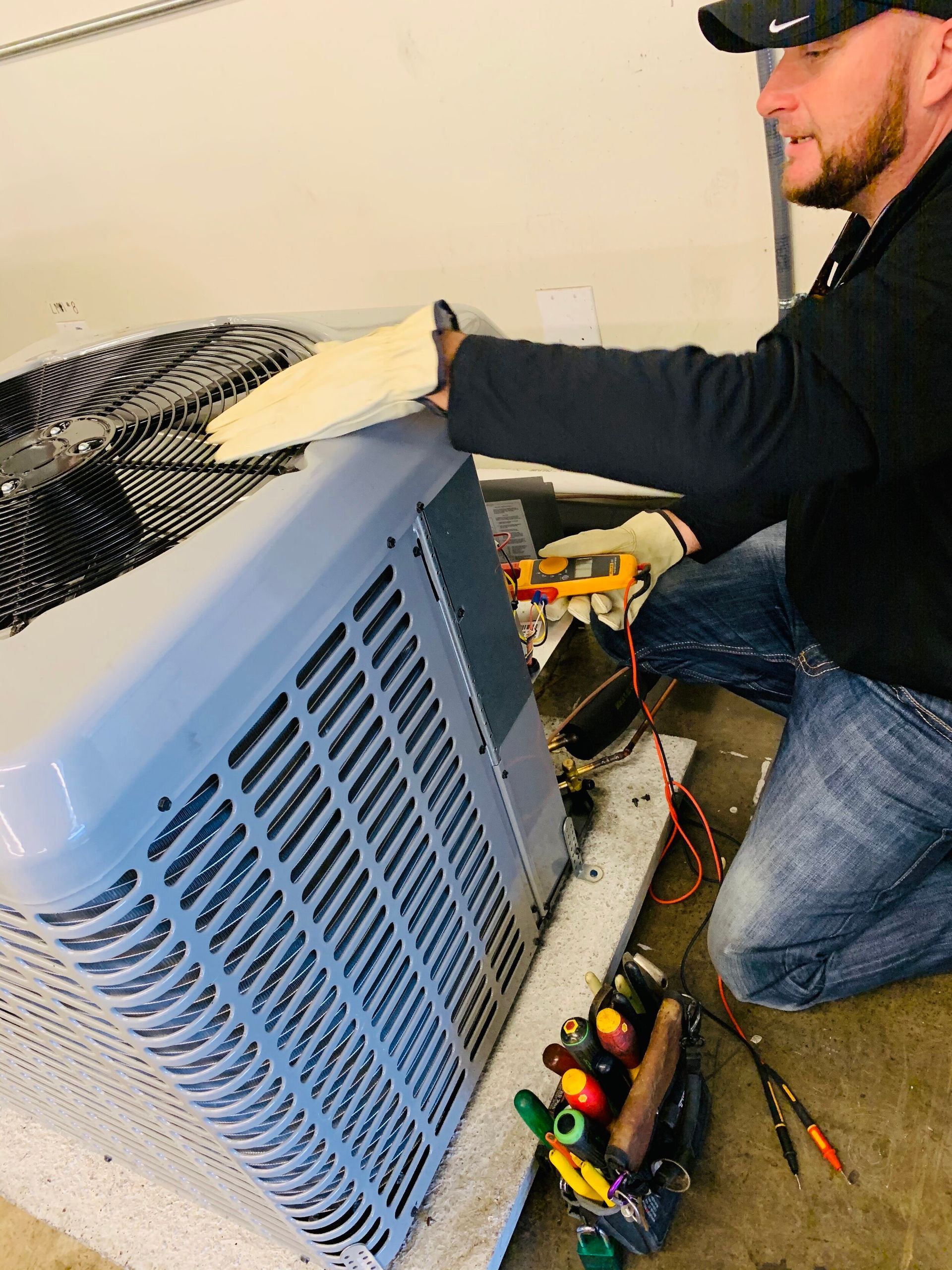 A man is working on an air conditioner in a garage.