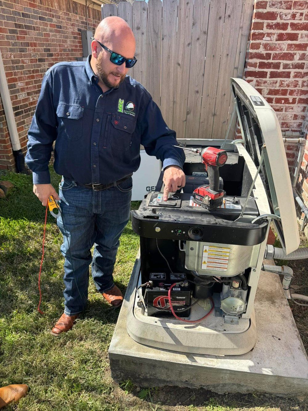 A man is standing next to a generator in a backyard.