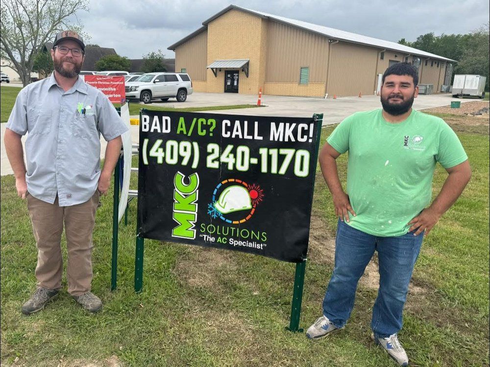 Two men standing next to a sign that says bad a / c call mkc