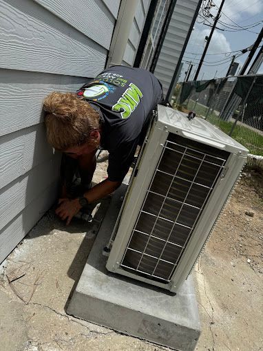 A man is working on an air conditioner outside of a building.