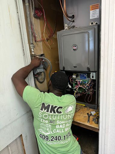 A man in a green shirt is working on an air conditioner.
