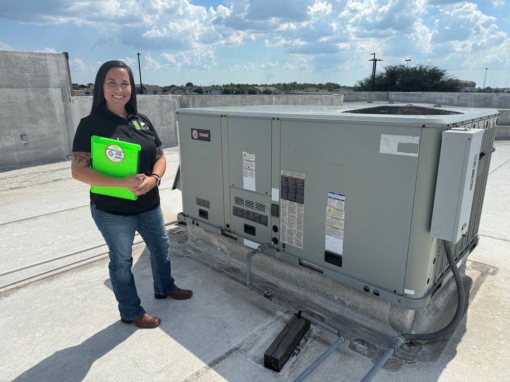A woman is standing on top of a roof next to a large air conditioner.
