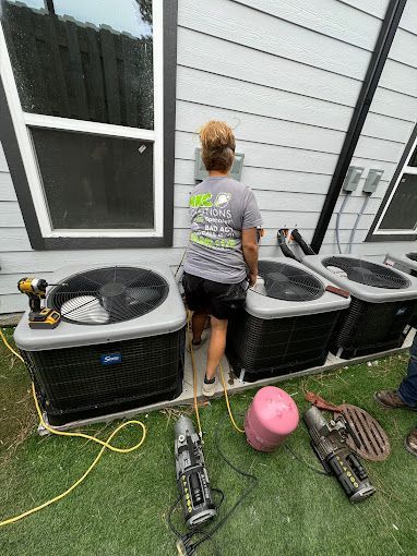 A woman is standing in front of a row of air conditioners.