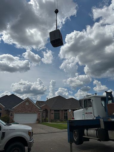 A truck with a crane attached to it is lifting a cube in the air.