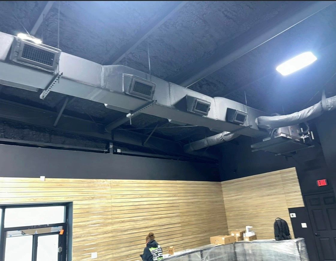 A room with a lot of air ducts hanging from the ceiling.