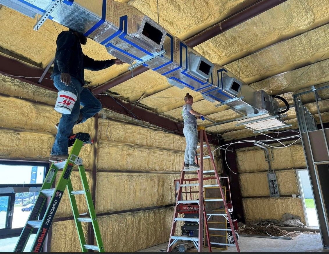 Two men are working on the ceiling of a building.
