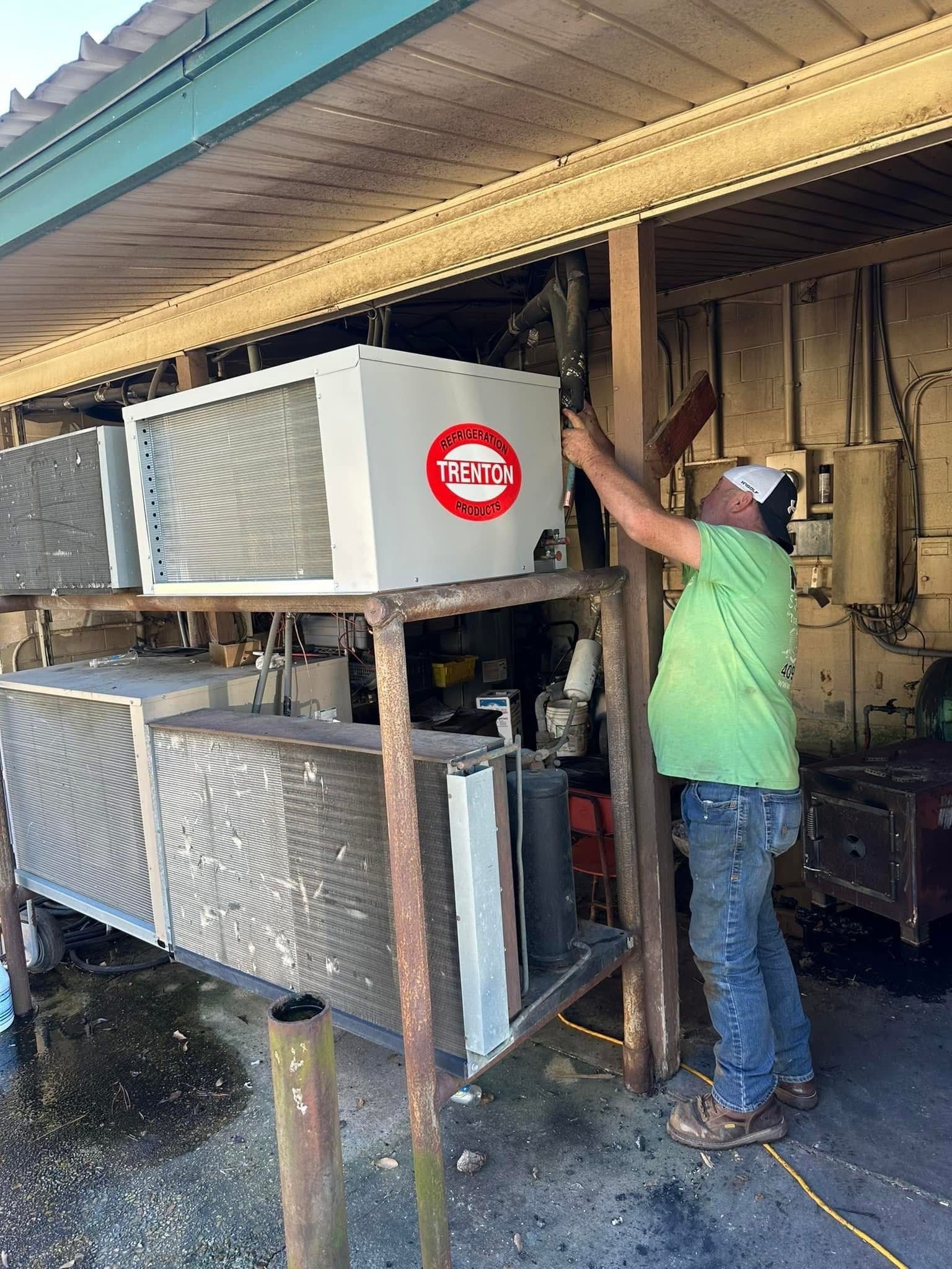 A man is working on an air conditioner outside of a building.