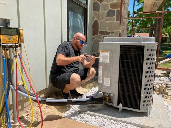 A man is working on an air conditioner outside of a house.