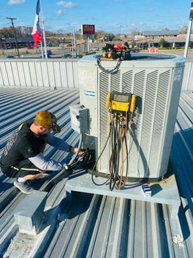 A man is working on an air conditioner on the roof of a building.