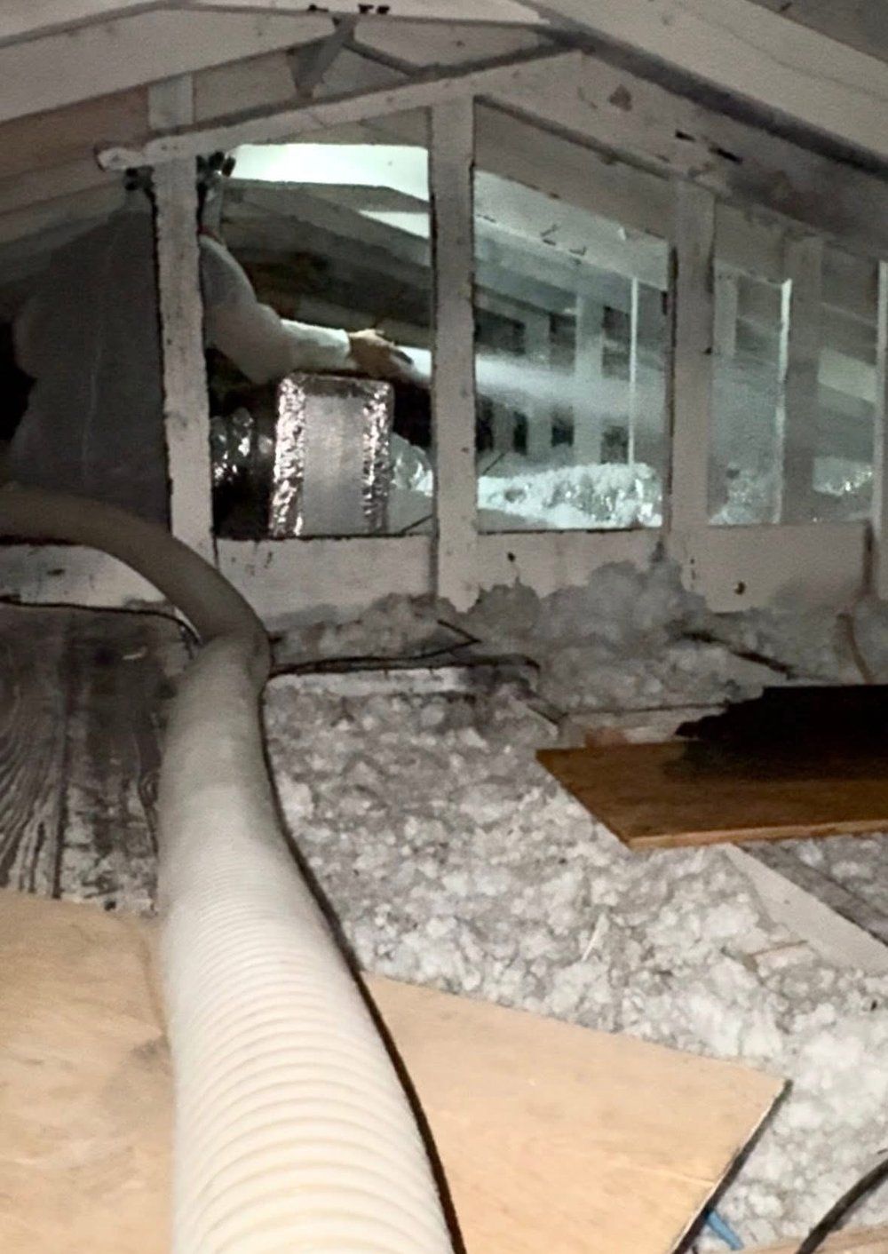 A person is standing in a room with a hose coming out of the ceiling.