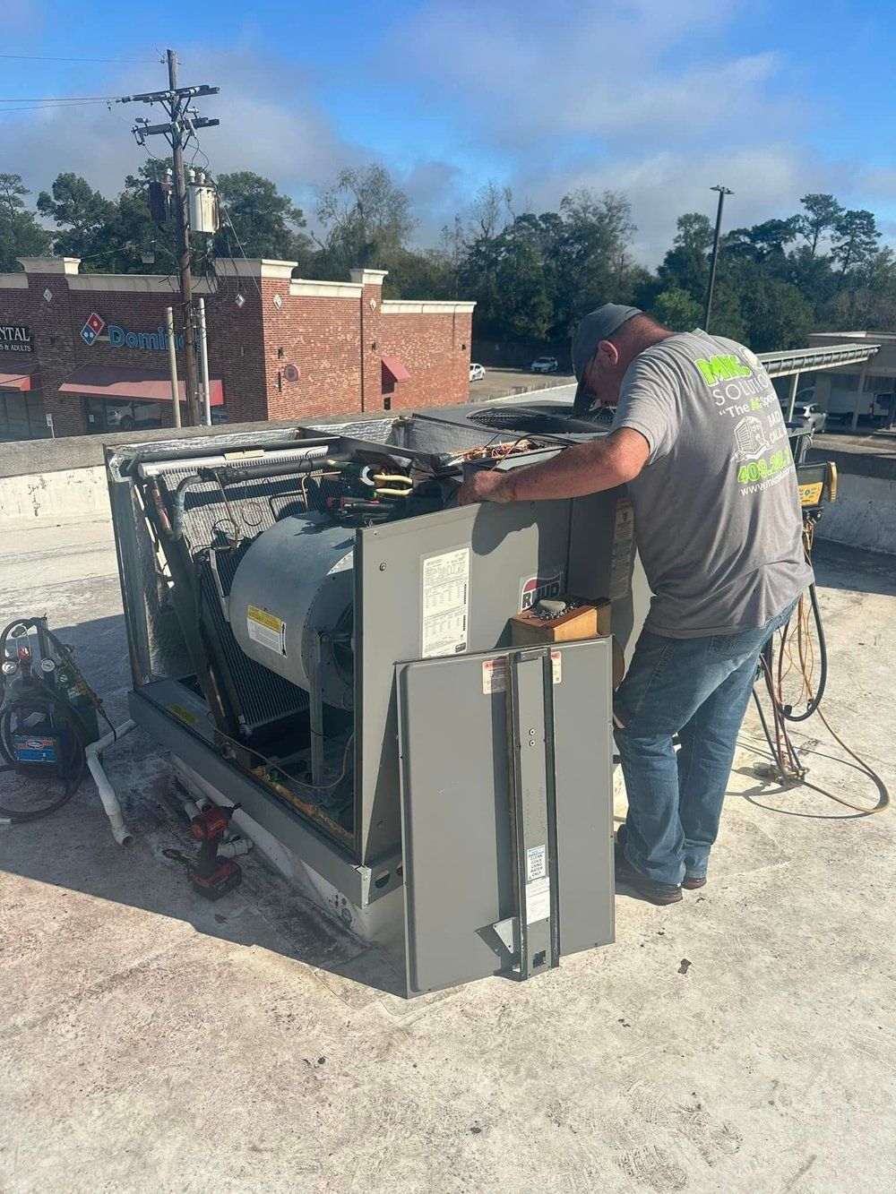 A man is working on a machine on the roof of a building.