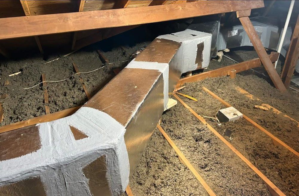 A wooden attic with a metal pipe going through it.