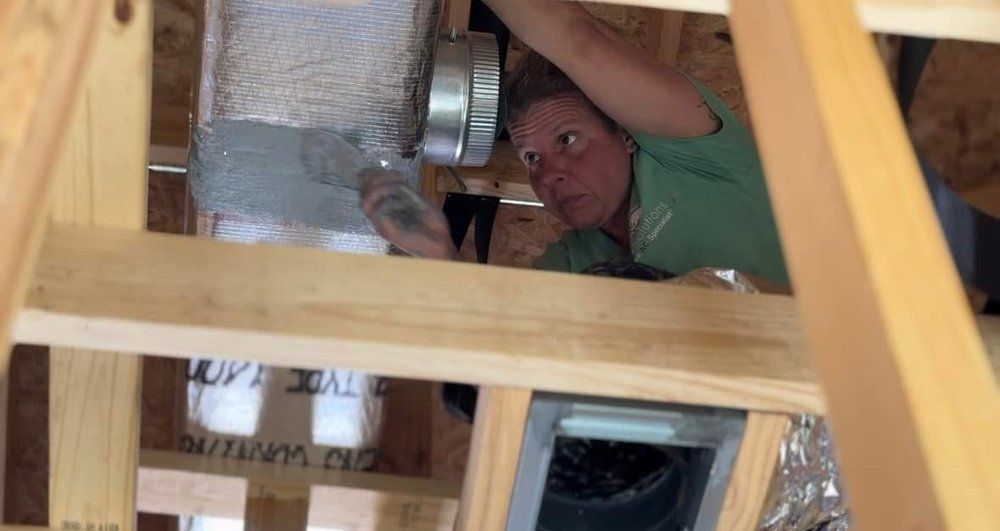 A man is working on a duct in the ceiling of a house.