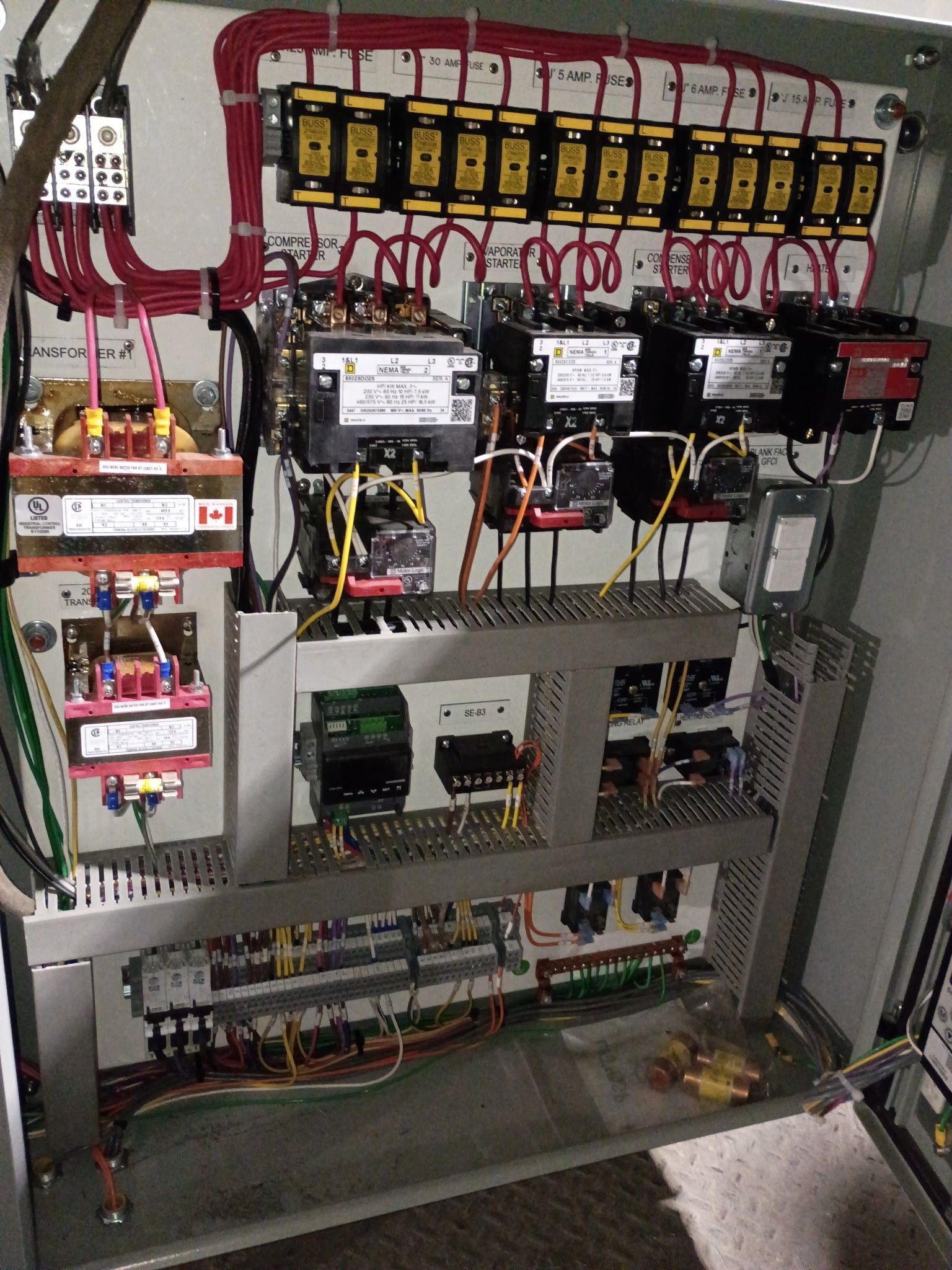 Electrical control panel with wires, relays, and circuit breakers.