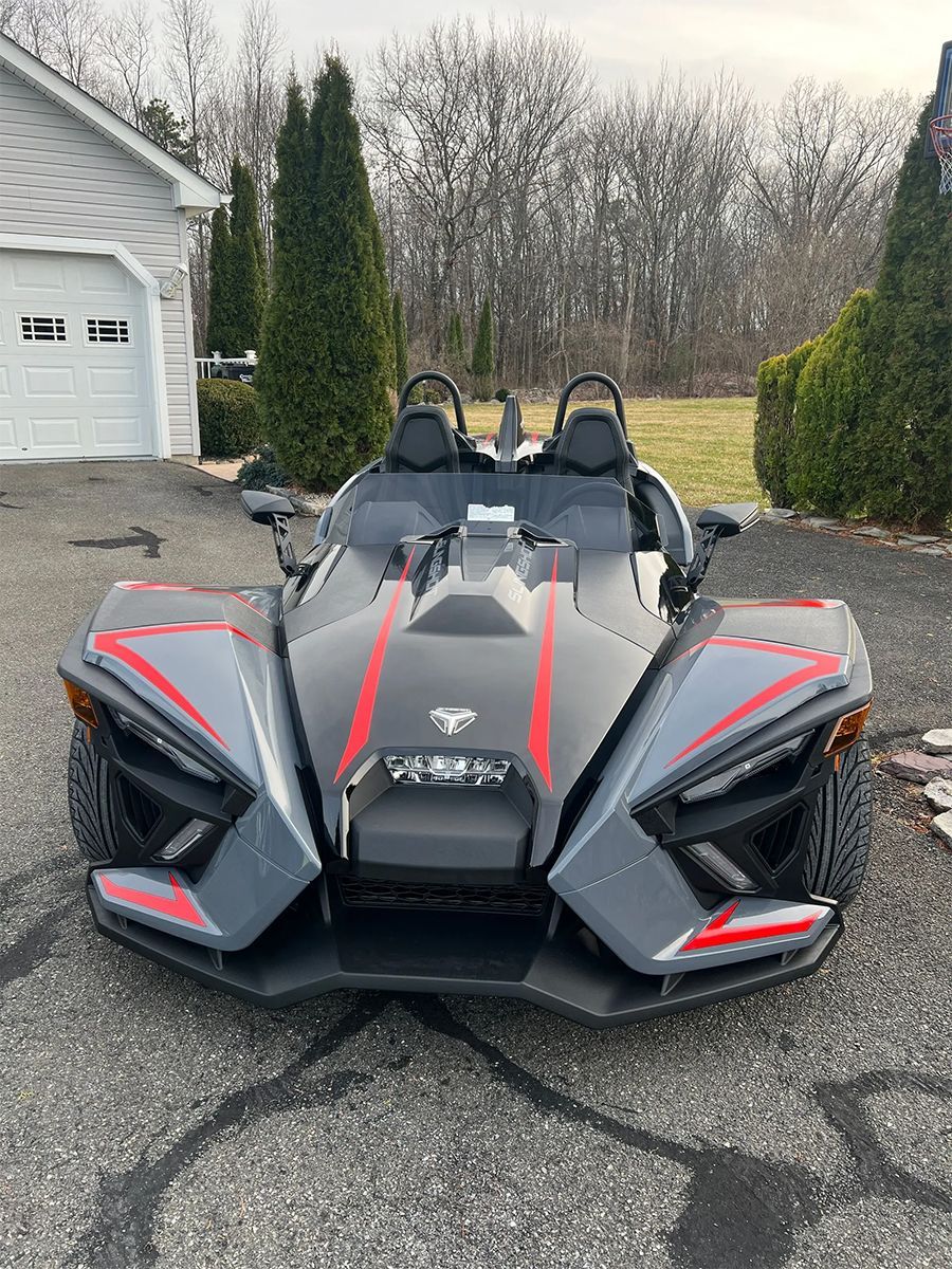 A slingshot is parked in front of a garage.
