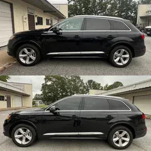Black midsize SUV parked beside a house in a driveway, shown from the side.