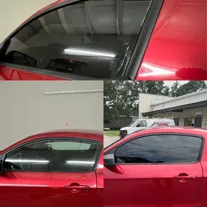 Red car with tinted side windows, shown in close-up and side view outside a building.