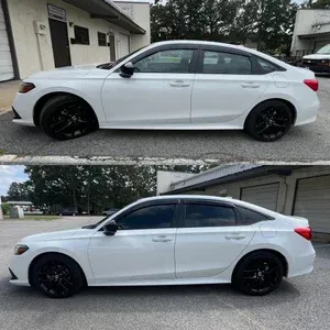 White four-door sedan with black wheels, shown in side view parked outside a house.
