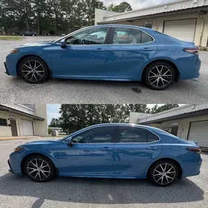 Blue sedan car shown in side view, parked outdoors near a building and trees.