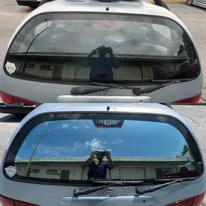Two car rear windows reflecting a person taking a photo; top window is cloudy, bottom is clear blue.