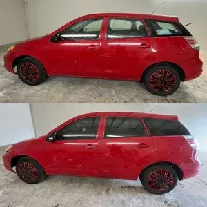 Side view of a red hatchback car shown twice, with black-and-red wheels, in a garage.