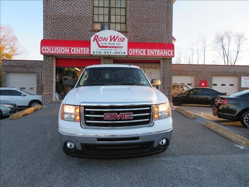 White GMC truck parked in front of a collision center with a red awning.