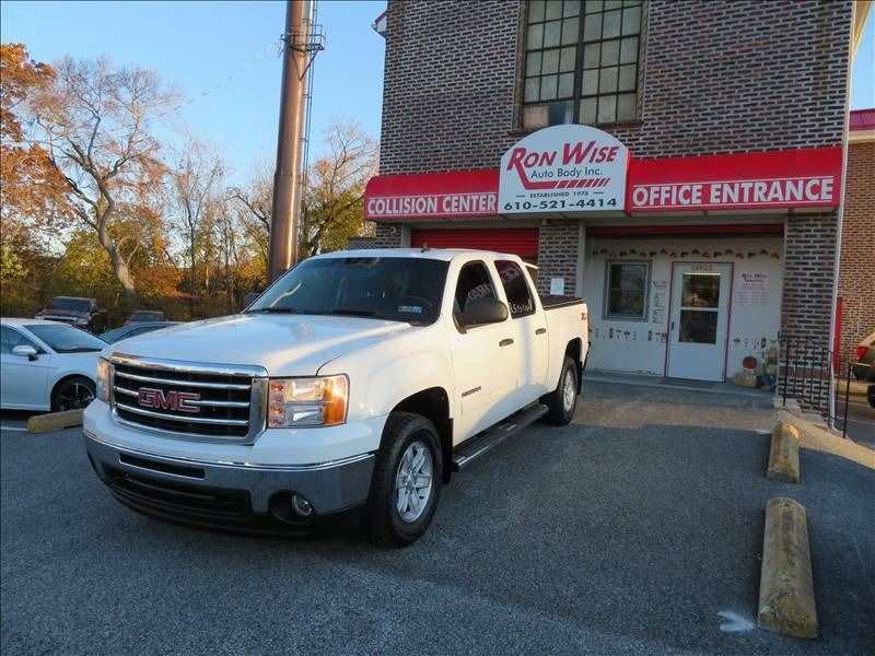 White GMC pickup truck parked in front of Ron West Collision Center office entrance.