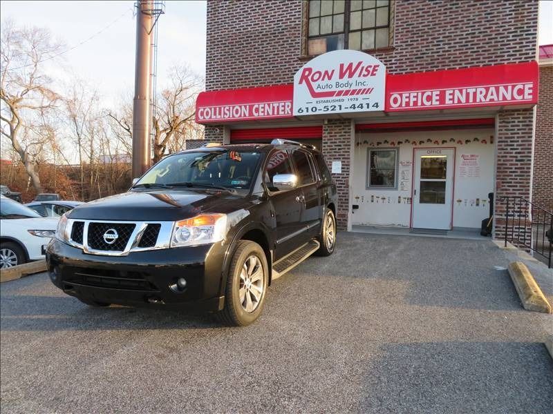 Black Nissan Armada parked in front of Ron Wise Auto Body shop with red awning.