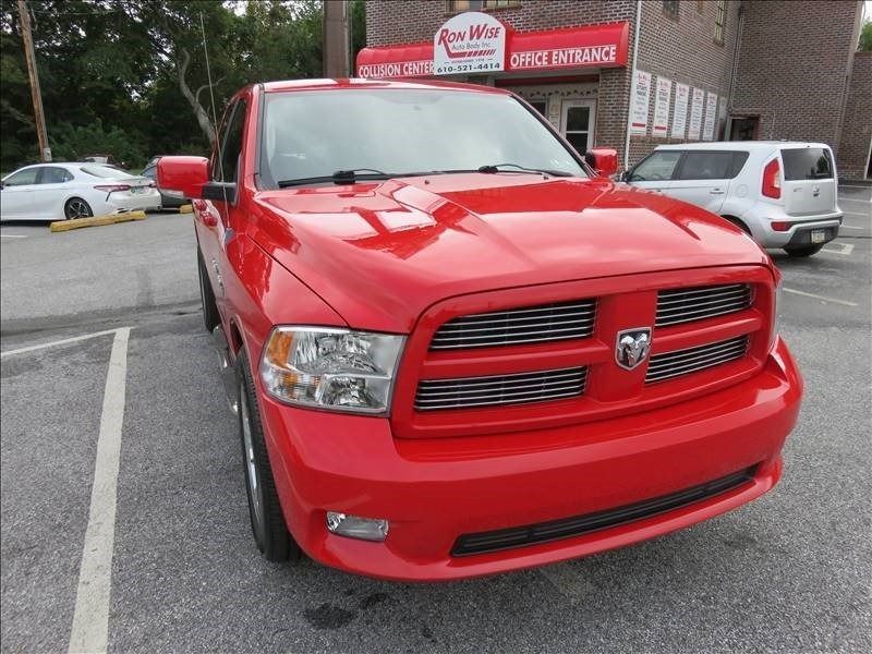 Red Dodge Ram truck parked in a lot. Brick building in the background.