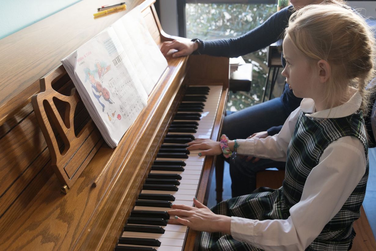 Two people in a music studio, one playing an electronic keyboard while the other sings into a microphone.