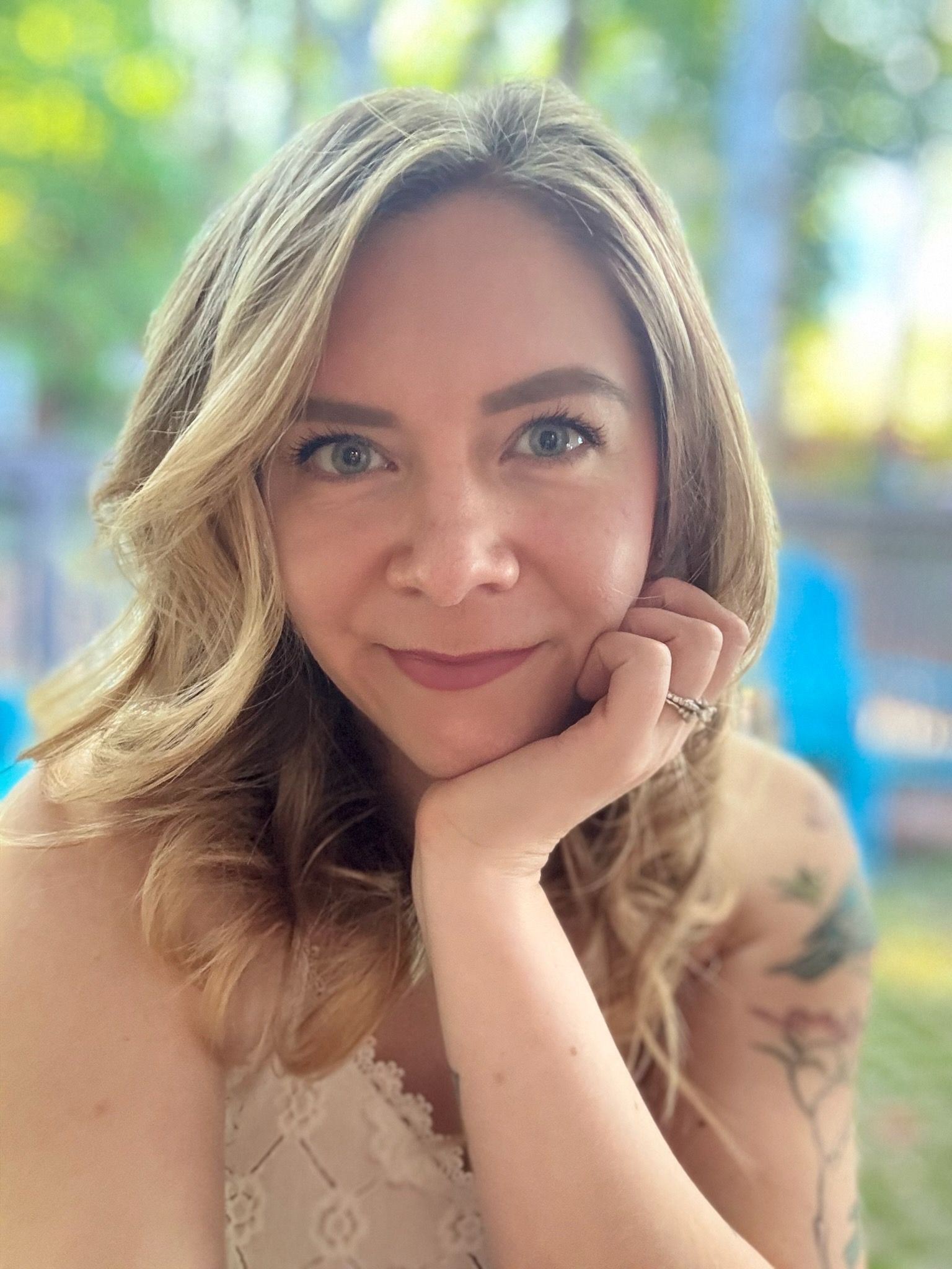 Woman with pink hair smiles, looking at the camera.