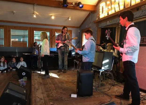 Band performing on stage in a venue. Musicians with guitars and a vocalist perform for an audience.