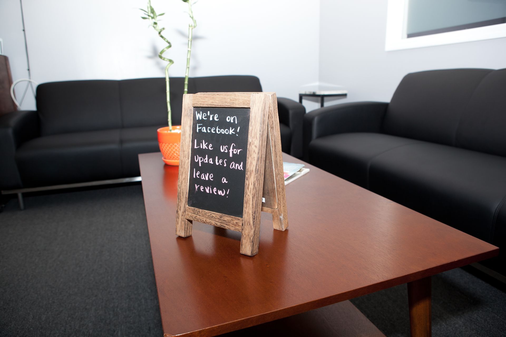 Black couches, coffee table, and sign that reads: