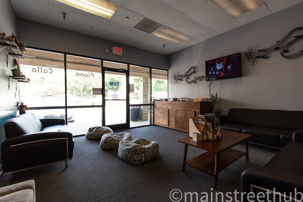 Waiting room with seating, a small table, a TV, and large windows.