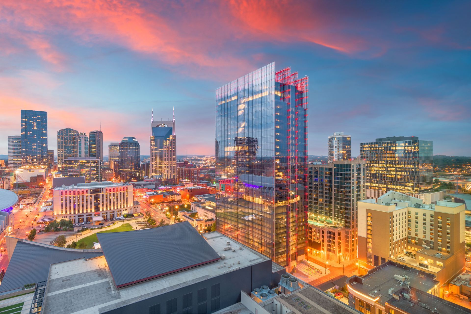 Nashville, Tennessee skyline at sunset with pink and blue sky, illuminated buildings.