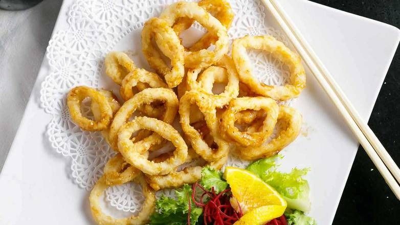 Fried calamari rings on a white plate with garnish and chopsticks.