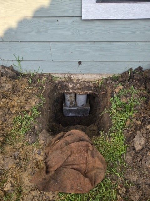 Hole dug in the ground next to a house foundation