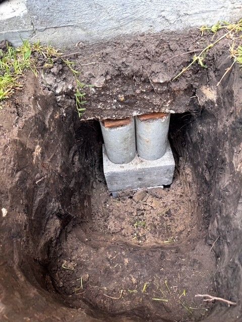 Excavation exposing two concrete pillars supporting a structure's base