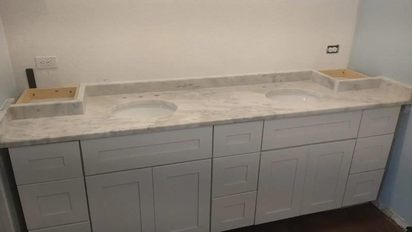 Gray vanity cabinet with marble countertop and double sinks in a bathroom or utility room
