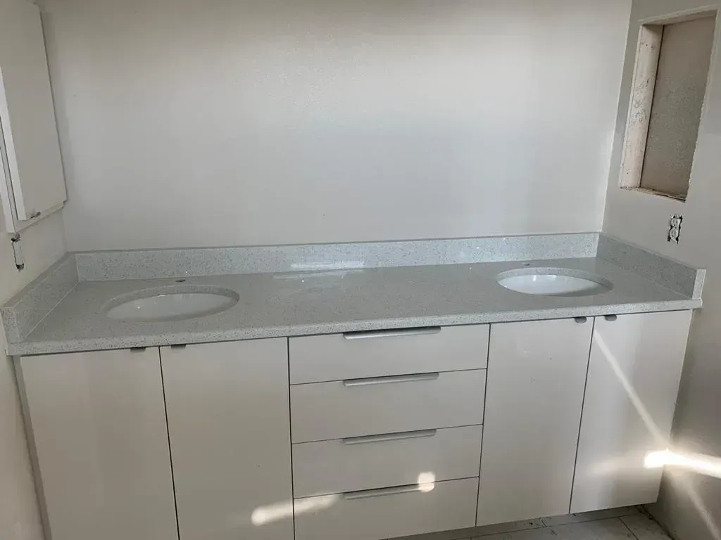 Empty bathroom vanity with double sinks, gray countertop, and white cabinets.