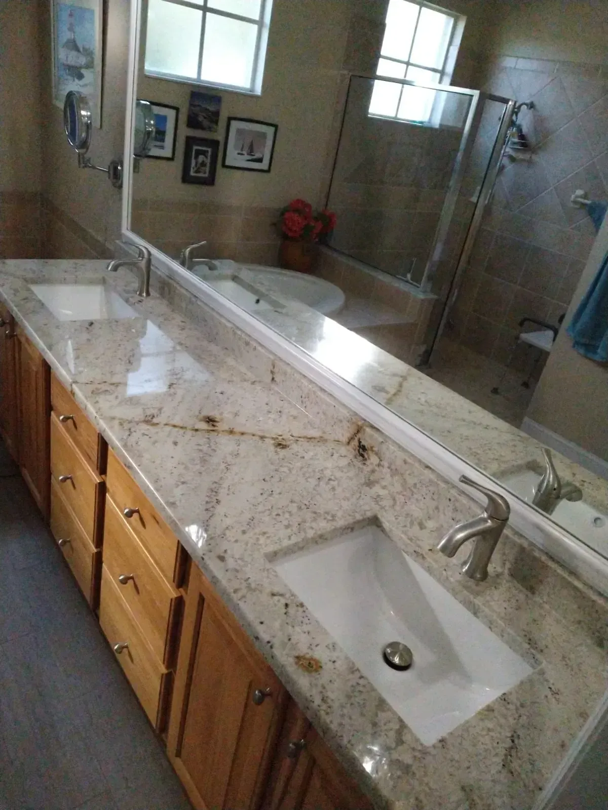 Bathroom vanity with double sinks, granite countertop, mirrors, and wooden cabinets