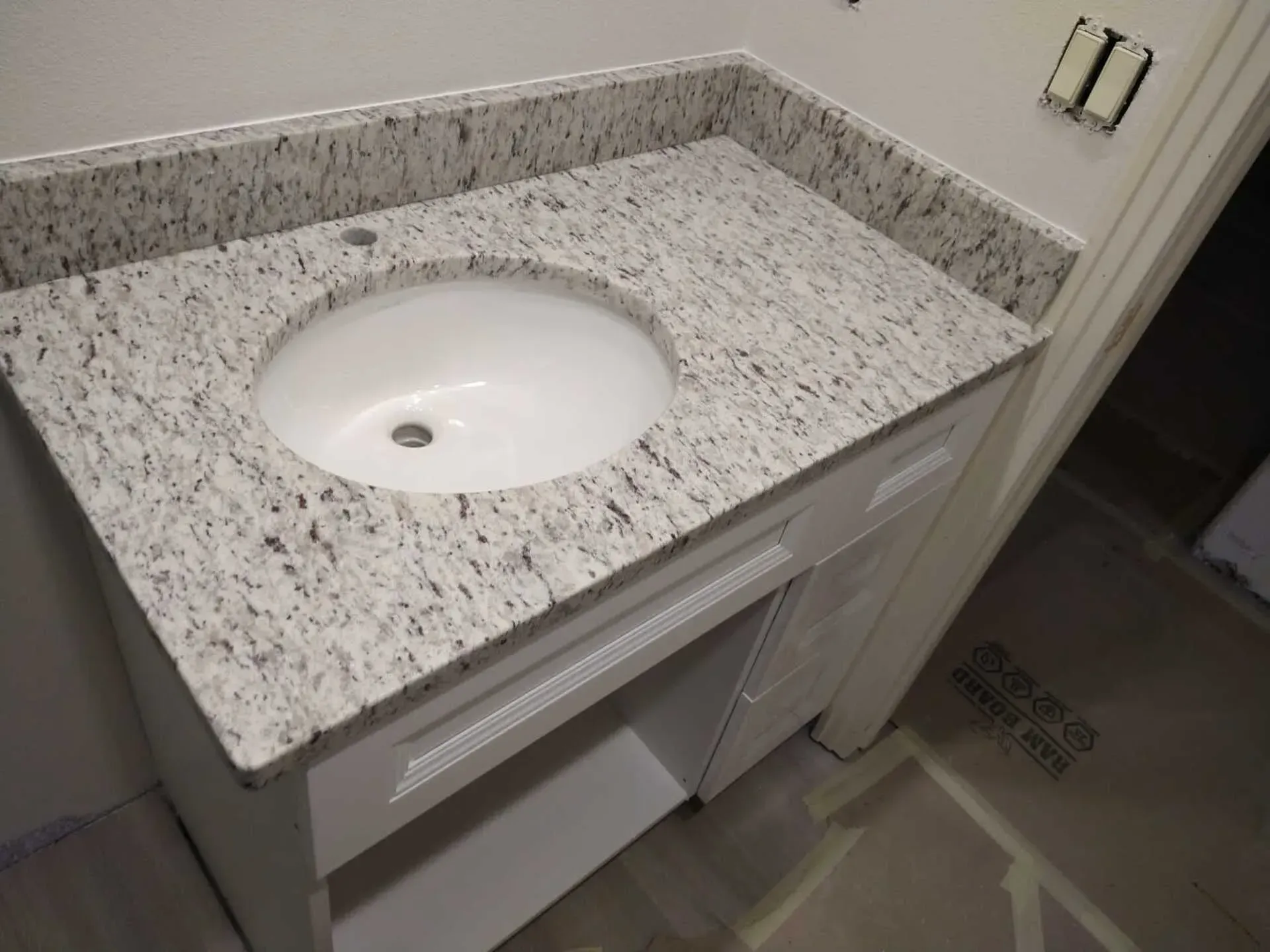 Bathroom vanity with speckled granite countertop and oval sink