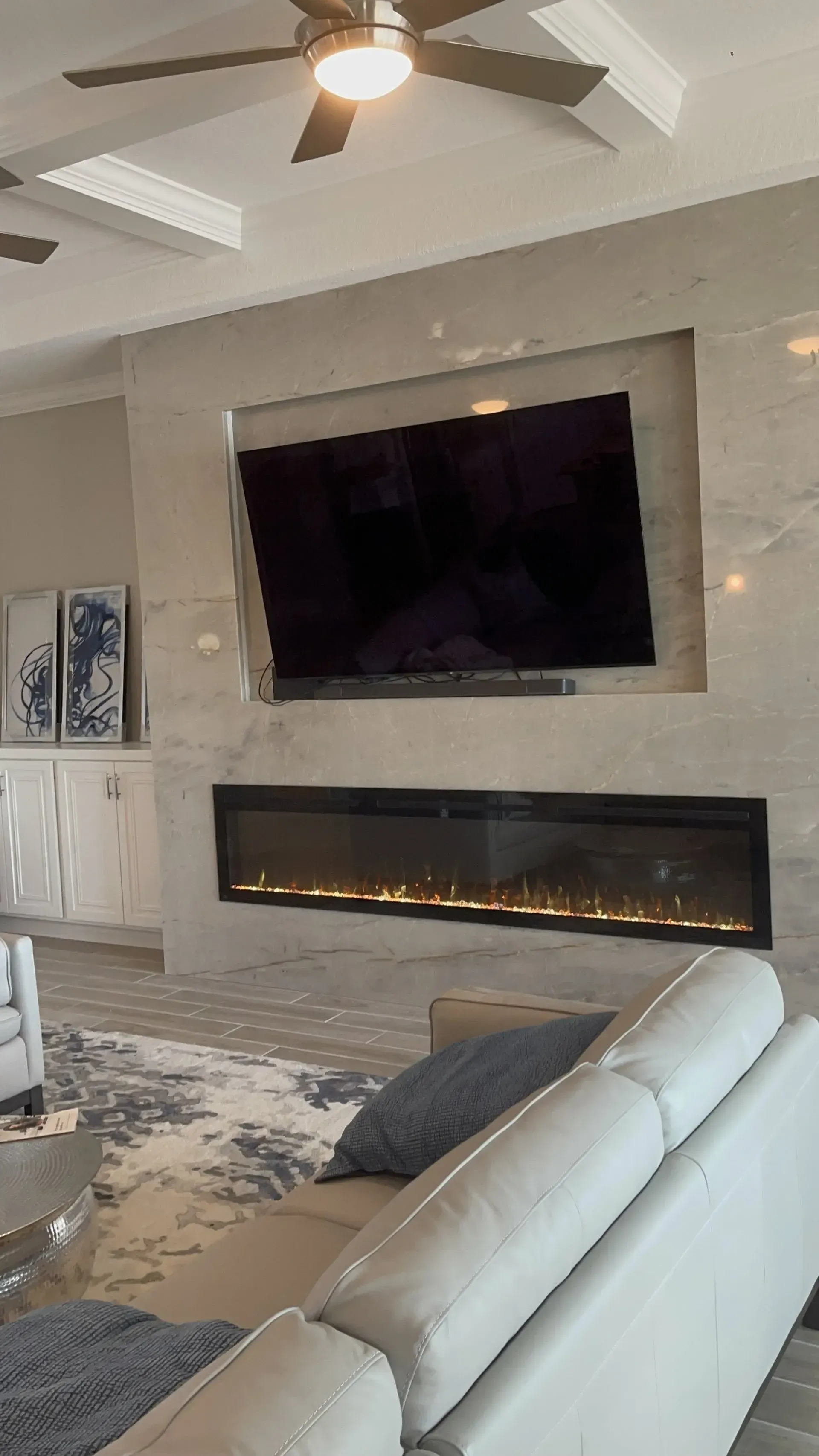 Modern living room with mounted TV above a long linear fireplace and white sectional sofa.
