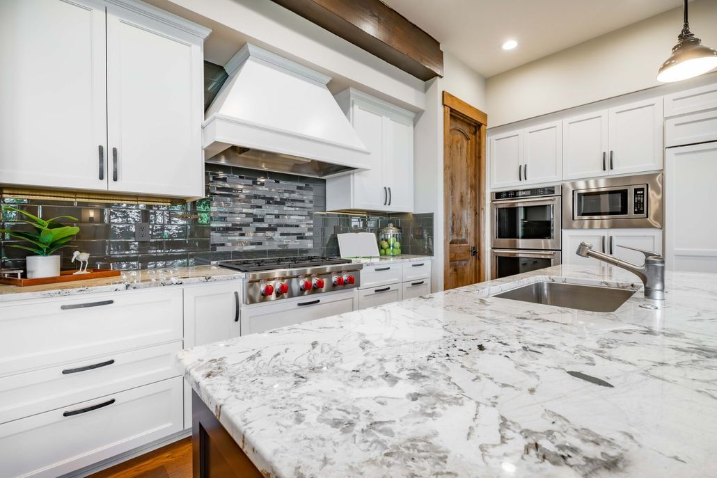 Modern kitchen with blue cabinets, granite island, and white refrigerator under recessed lights