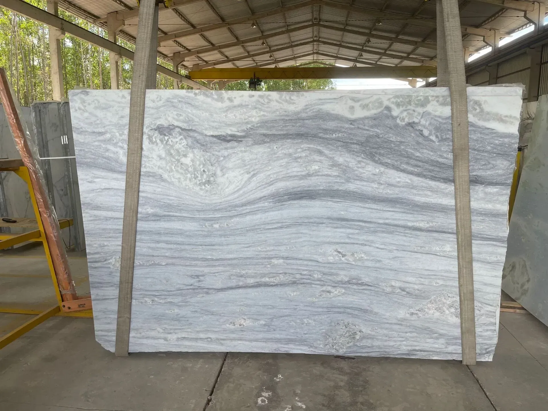 Large white-and-gray veined stone slab displayed in a warehouse or workshop